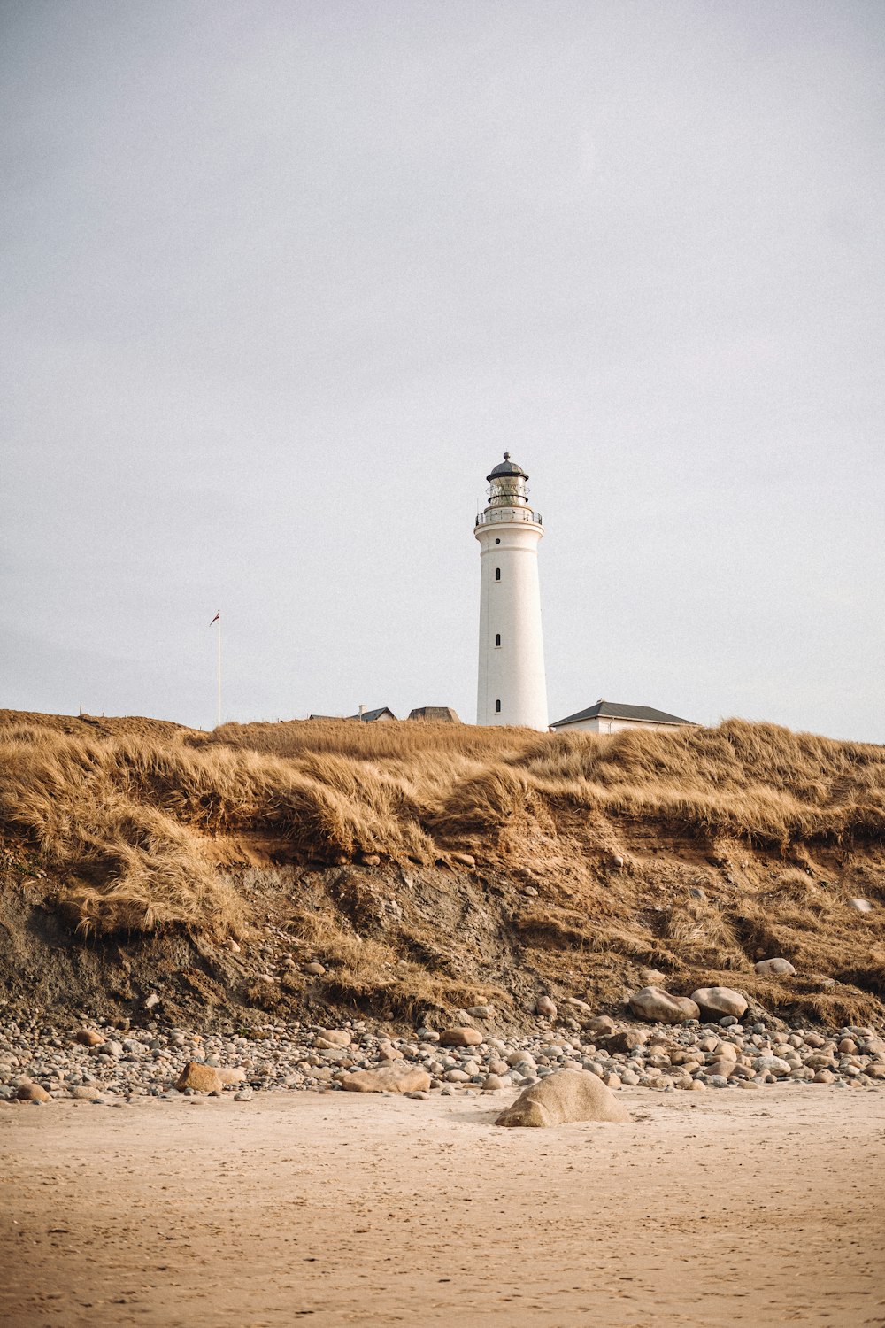 white lighthouse on brown grass field under gray sky