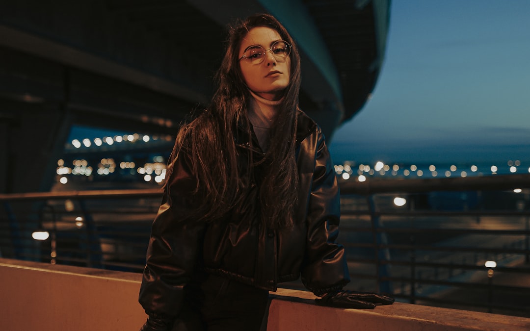 woman in black leather jacket standing near brown wooden table