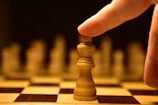 Close-up of hands moving chess pieces symbolizing careful moves and intuition