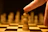 A focused young student thoughtfully planning a chess move under soft, warm lighting.