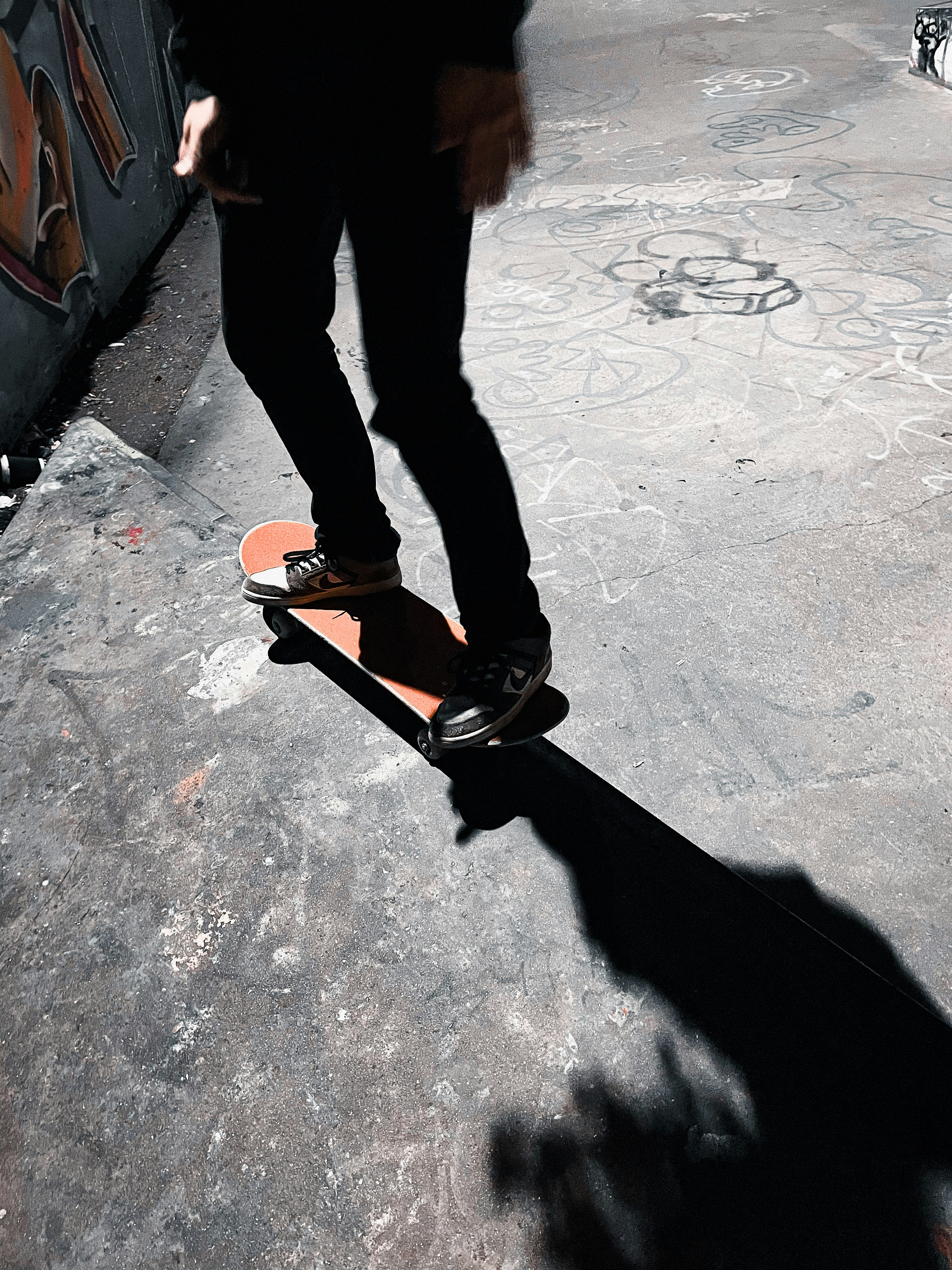 person in black pants and black and orange sneakers standing on gray concrete floor