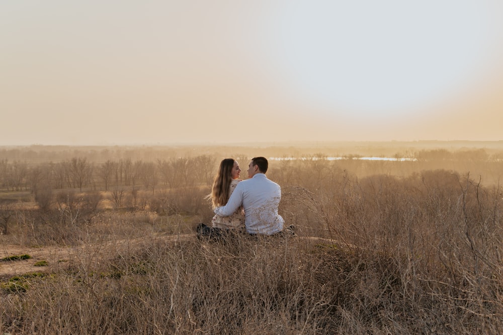 couple sitting on grass field during daytime