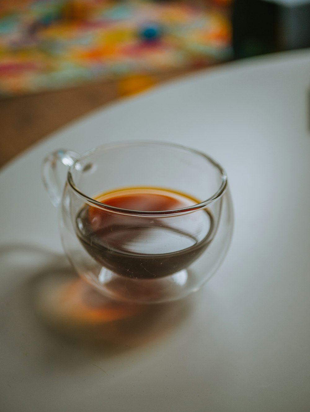 taza de té de vidrio transparente sobre mesa blanca