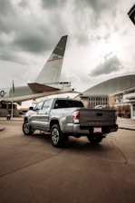 white crew cab pickup truck parked near white airplane