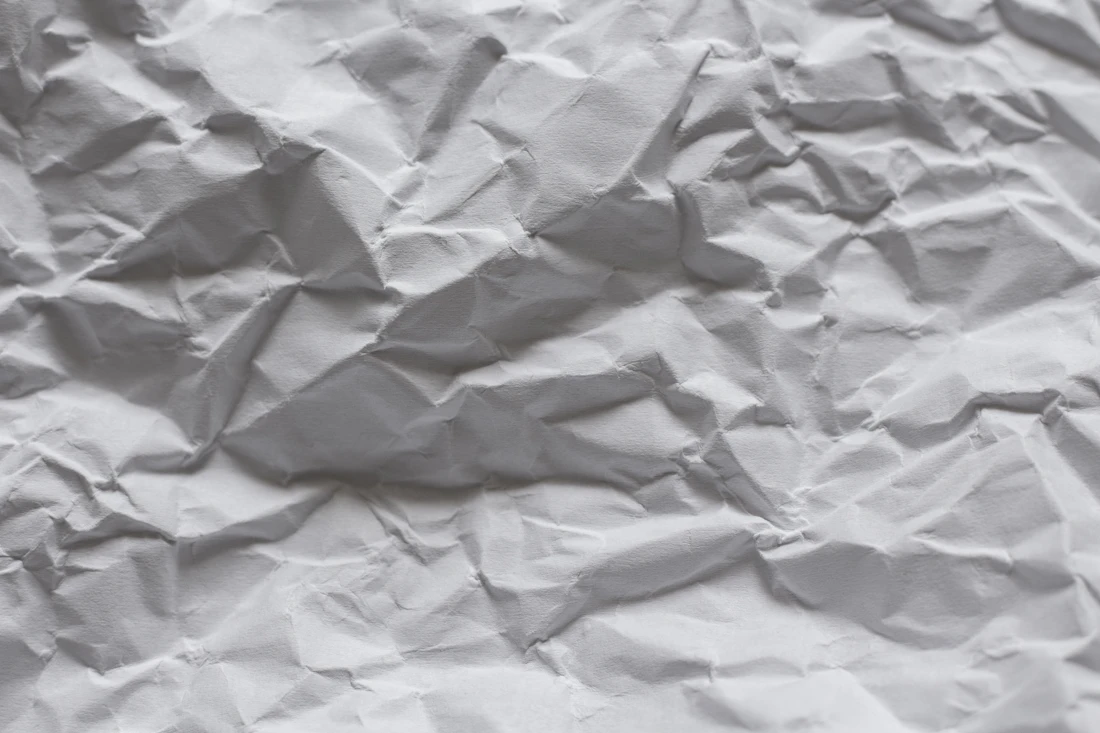 A sheet of white paper with deep creases and folds (stand-in for frown lines)