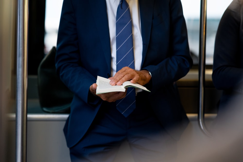 man in blue suit jacket reading book