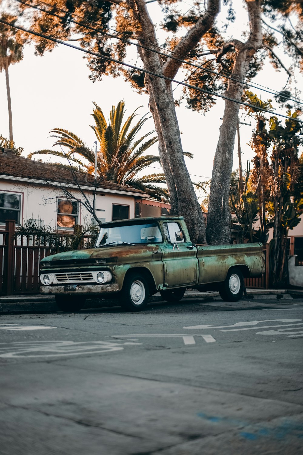 white and brown single cab pickup truck parked near brown wooden house during daytime