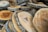 Roughly cut slices of wood with bark edges are stacked atop one another. The surface of each slice exhibits natural wood grain patterns and varying shades of brown.