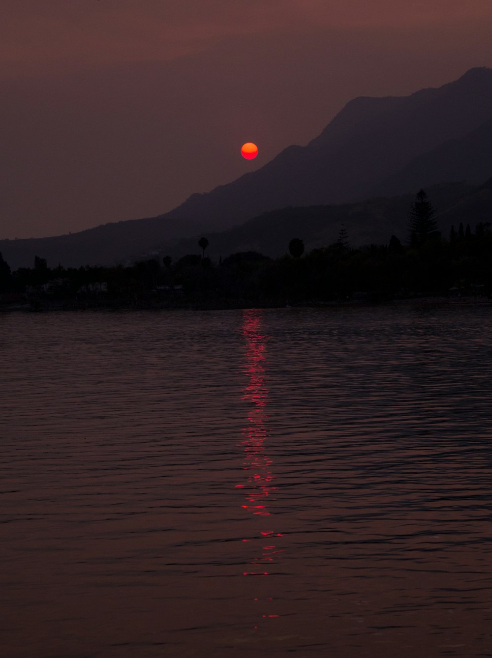 body of water near mountain during sunset