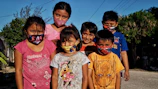 A group of kids proudly displaying their handmade paper masks with bright smiles.