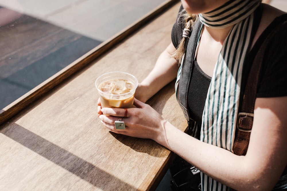 woman in black and white striped shirt holding clear drinking glass