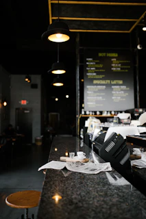 Ultra-realistic shot of the café’s sleek black marble counter illuminated by warm ambient lighting.