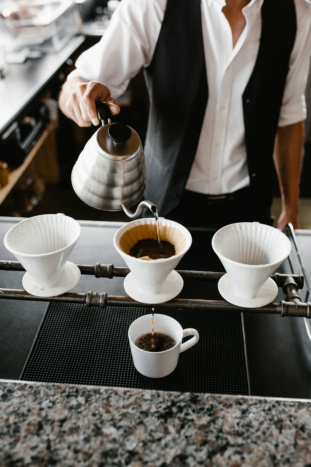 personne versant du café sur une tasse en céramique blanche