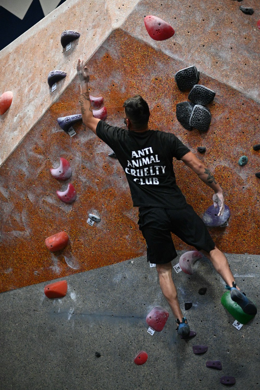 Homme en t-shirt noir et blanc à col rond et short noir debout sur du béton brun