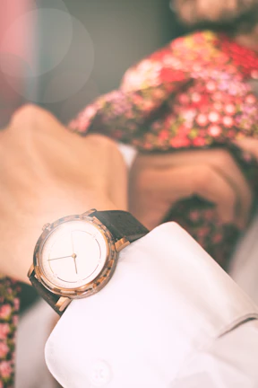 Hands adjusting a crisp white dress shirt cuff with a modern silver watch.
