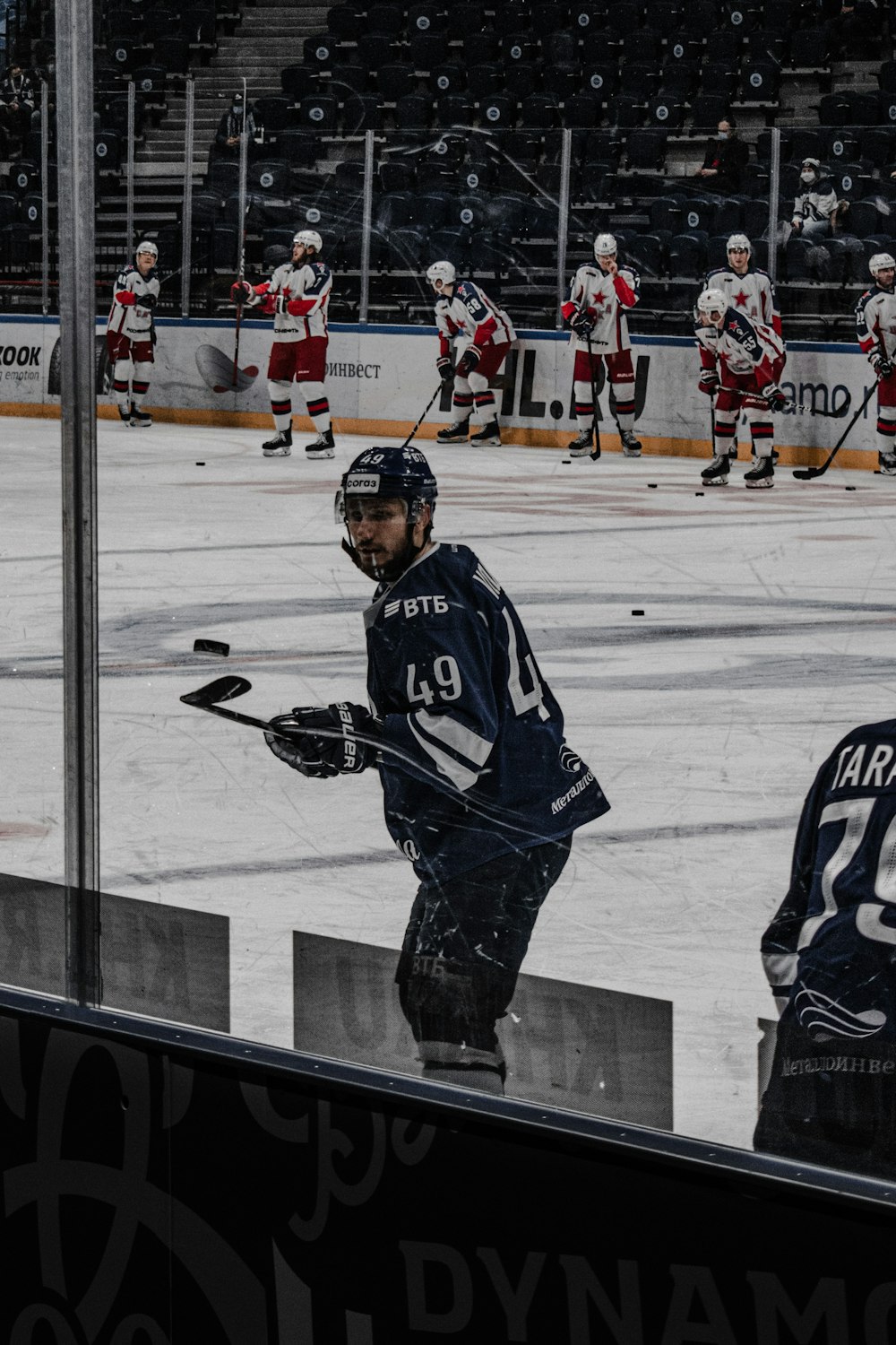 man in black and white ice hockey jersey shirt and gray pants standing on ice hockey