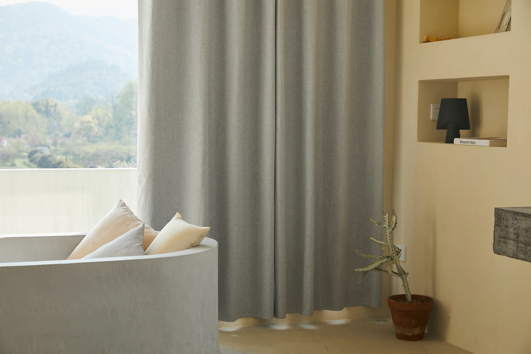 A soft white cotton cushion styled on a minimalist neutral couch