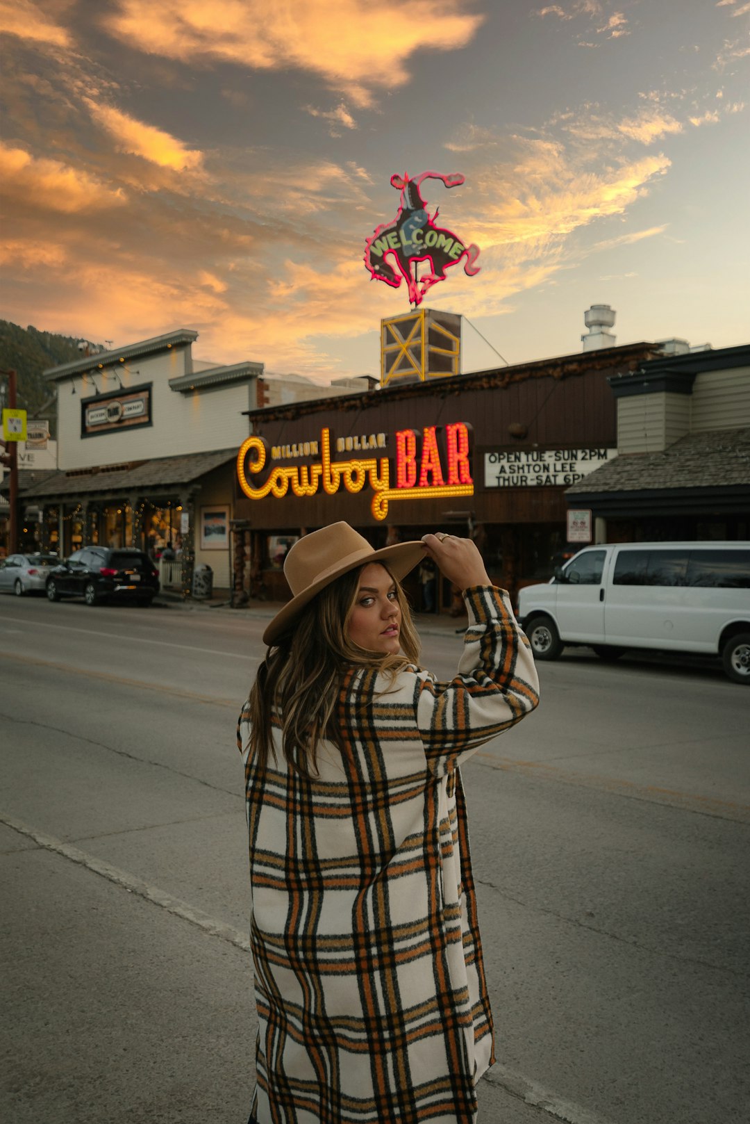 woman in brown cowboy hat standing on sidewalk during daytime