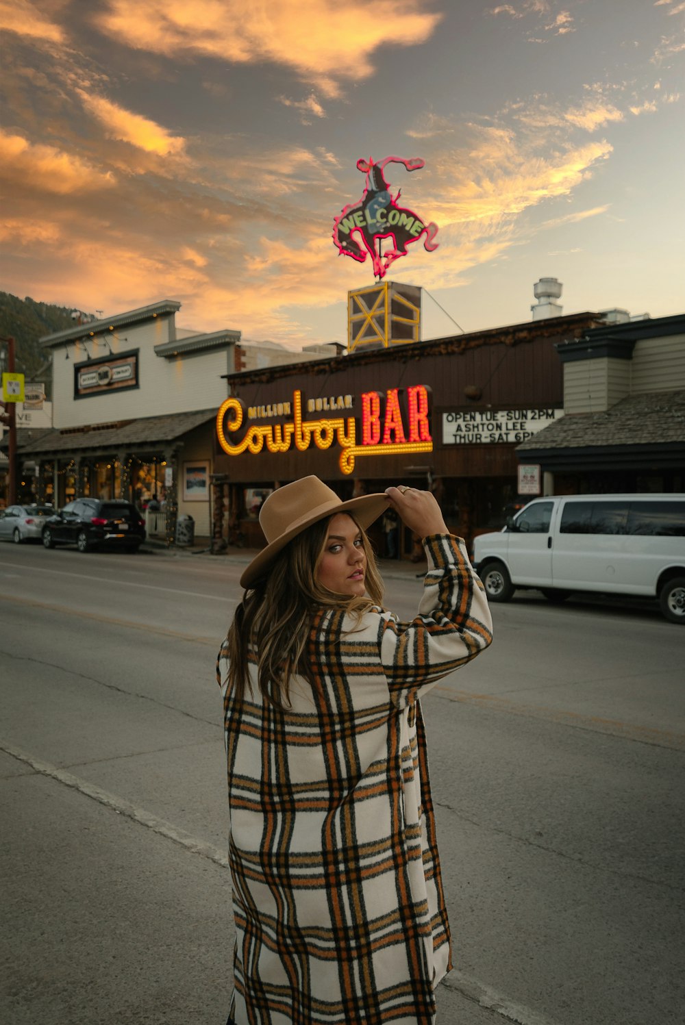 mulher no chapéu marrom do cowboy em pé na calçada durante o dia