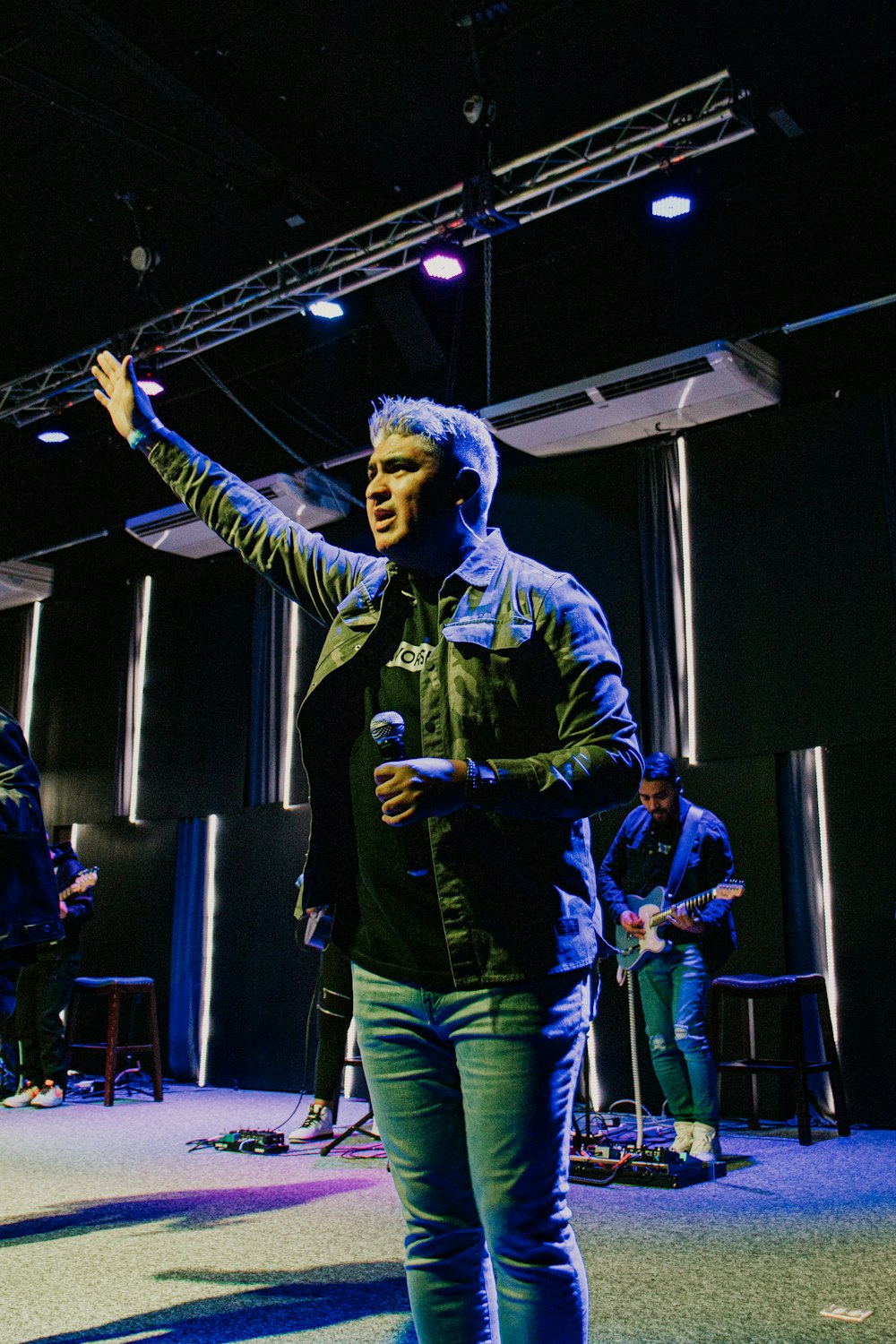 man in blue and green jacket and pants holding microphone