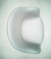A sleek, minimalist event chair in ivory and cacao tones set against a bright, airy backdrop.