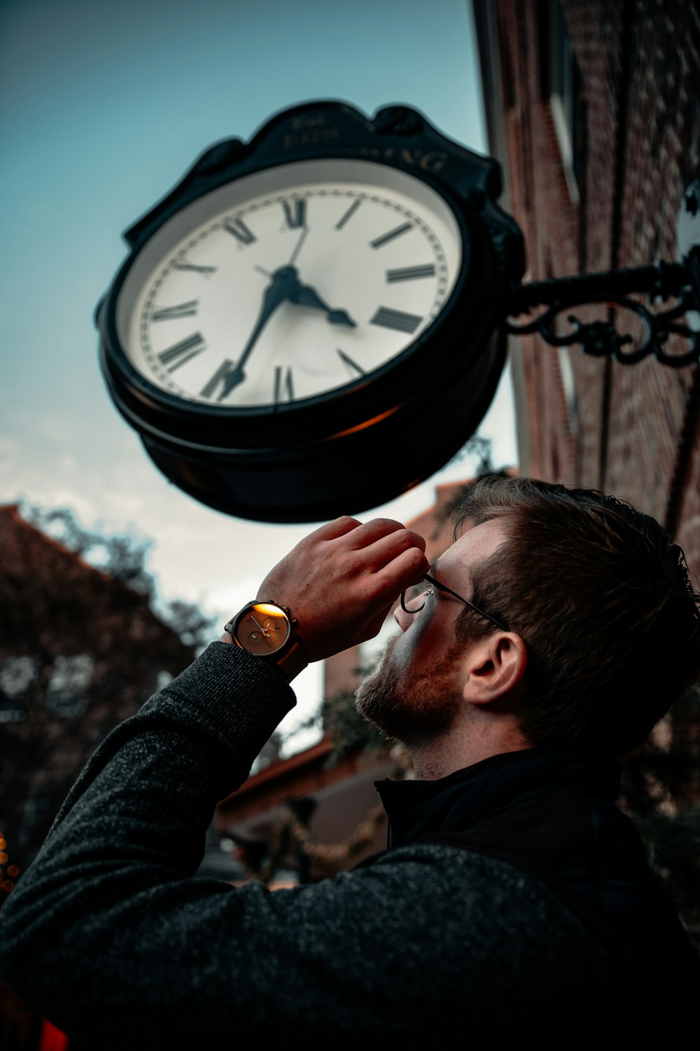 man in black long sleeve shirt holding black round analog watch