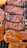 Various cuts of meat are sizzling on a grill, featuring distinct grill marks and a glossy glaze from the sauce. The pieces range in color from deep brown to reddish orange, indicating different levels of cooking and seasoning.