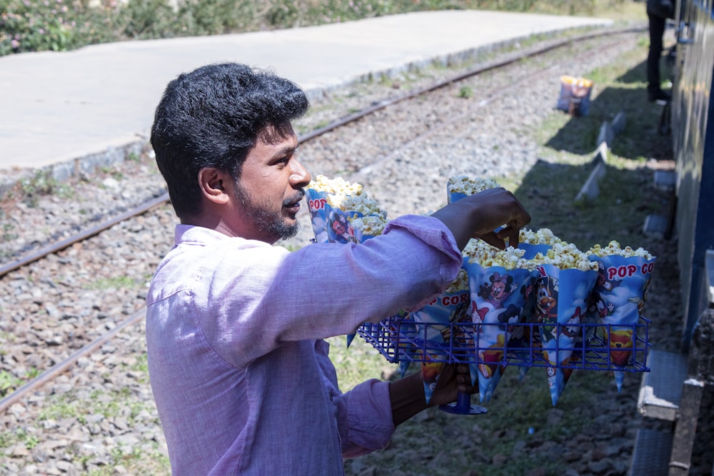 man in purple dress shirt holding blue flowers