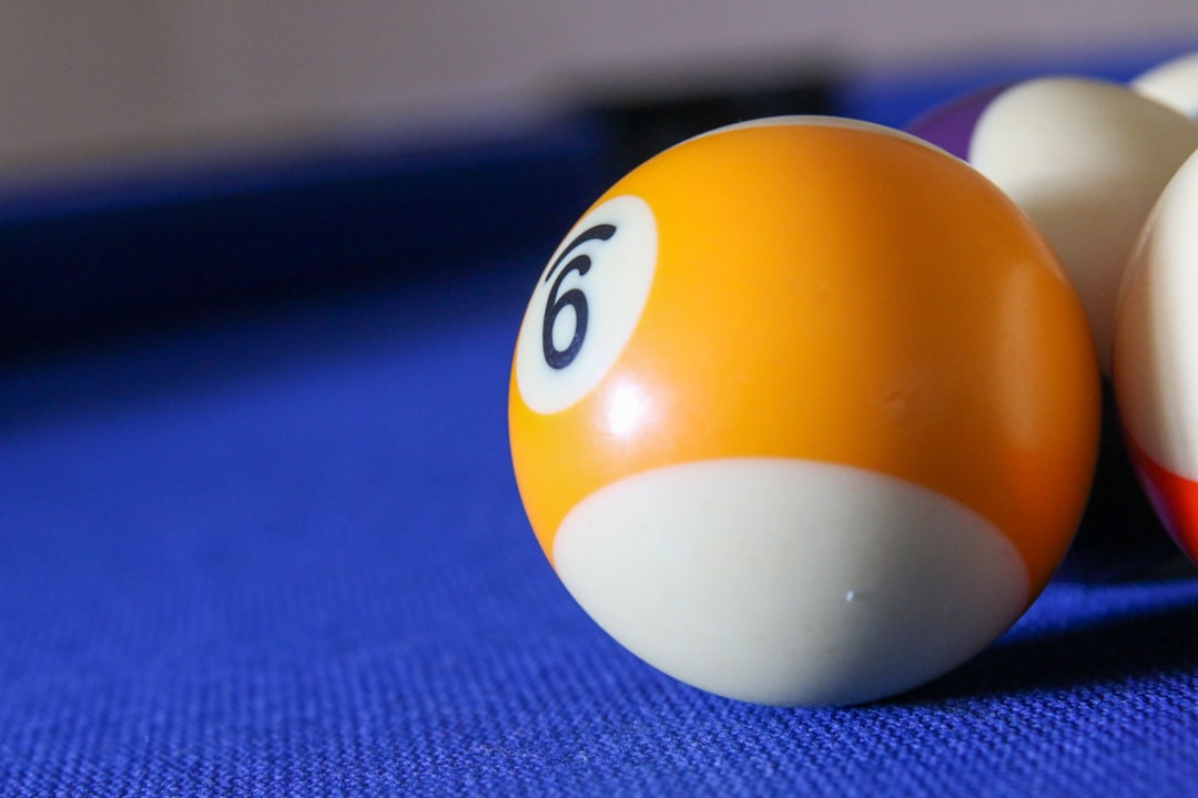 white and orange billiard ball on blue textile