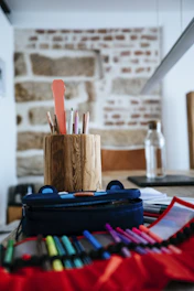 A variety of pencils and pens in a rustic cup on a desk