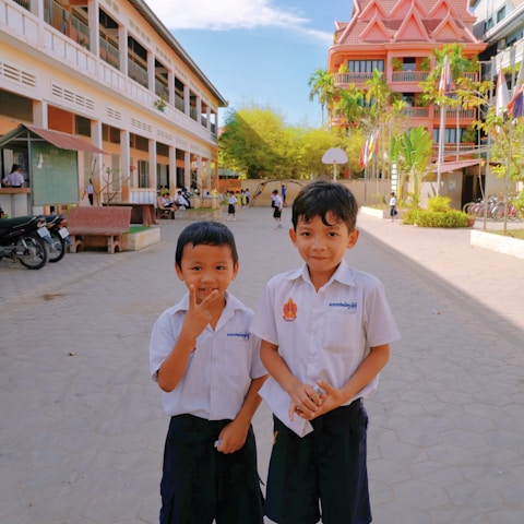 A diverse group of students wearing stylish school uniforms, smiling and interacting in a schoolyard.