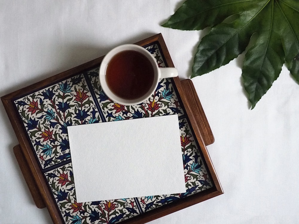 Taza de cerámica blanca sobre mantel floral blanco y azul