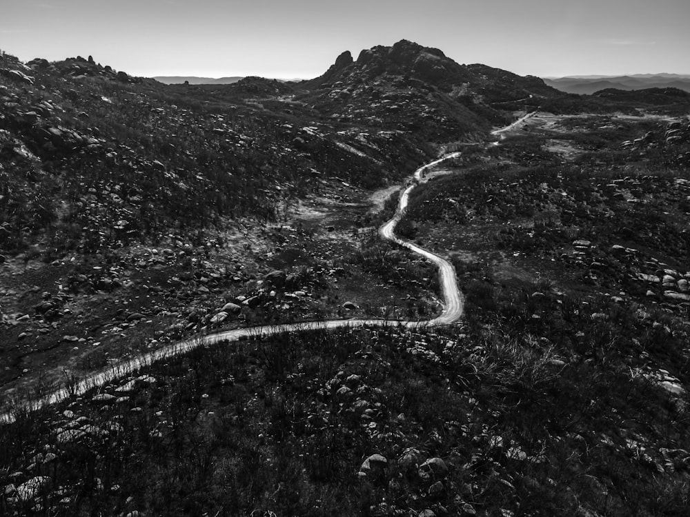 grayscale photo of road between mountains