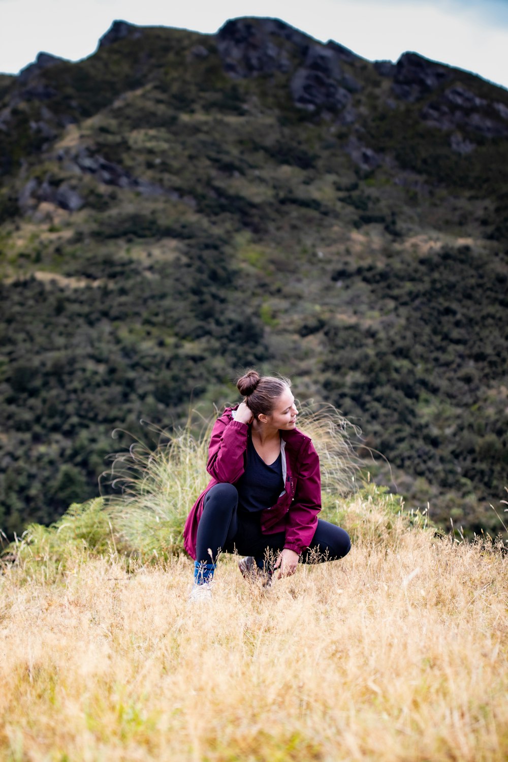 woman in red jacket sitting on grass field during daytime