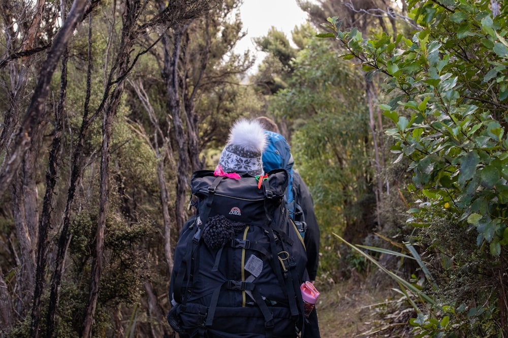 person in white fur jacket and black backpack standing on forest during daytime