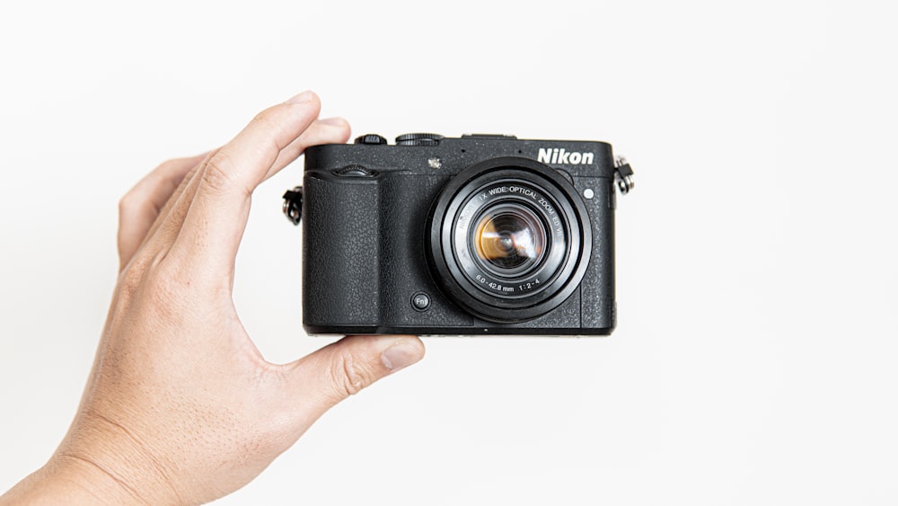 person holding black camera on white background