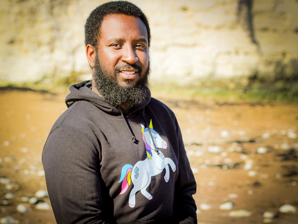 man in black hoodie standing on brown field during daytime