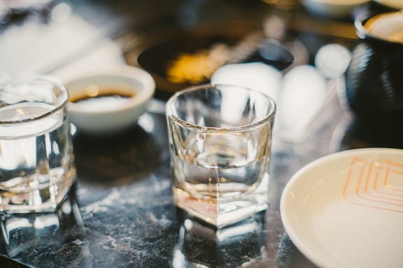 A serene image of a glass of water on a dining table with elegant cutlery.