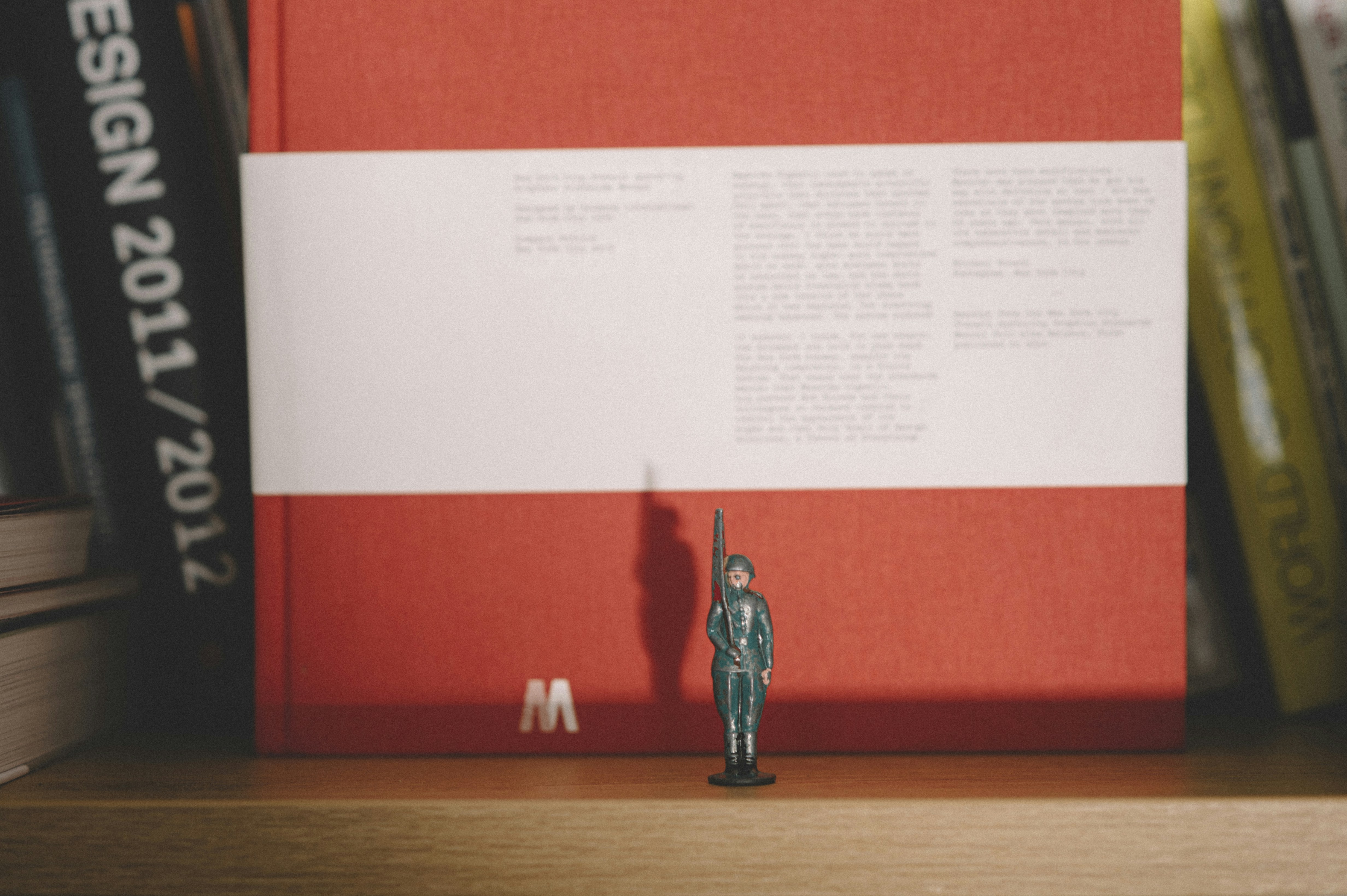 A toy soldier stands at attention on a bookshelf.