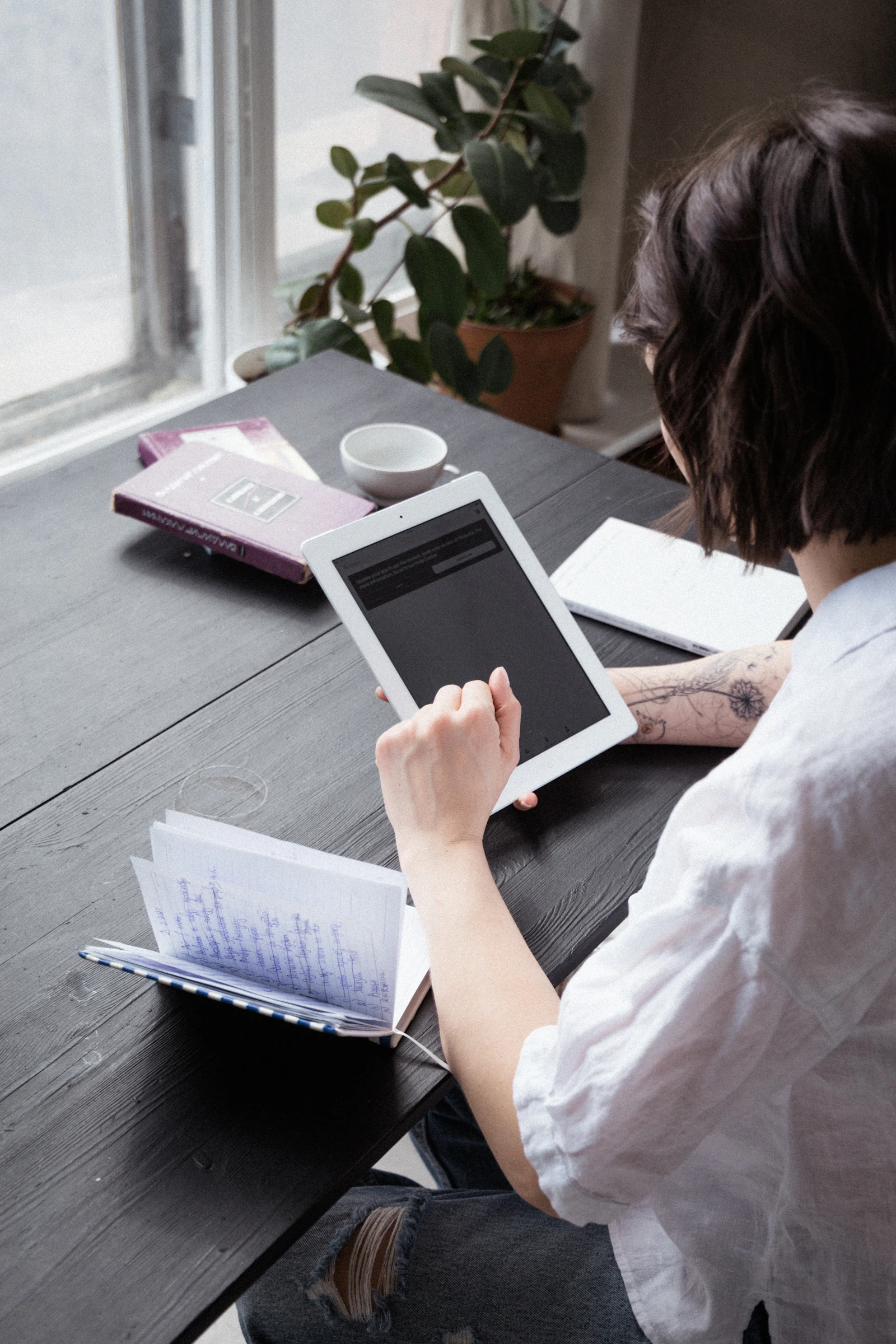 A professional reviewing documents on a tablet by a bright window