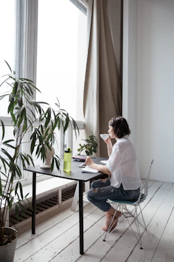 Portrait of Cathy Secreto working at her minimalist home office with a laptop and coffee.