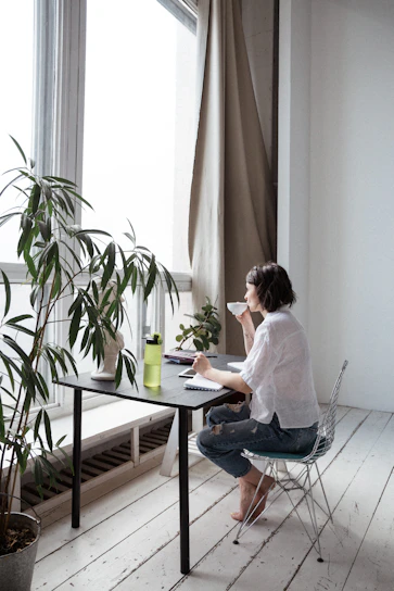 Portrait of Cathy Secreto working at her minimalist home office with a laptop and coffee.