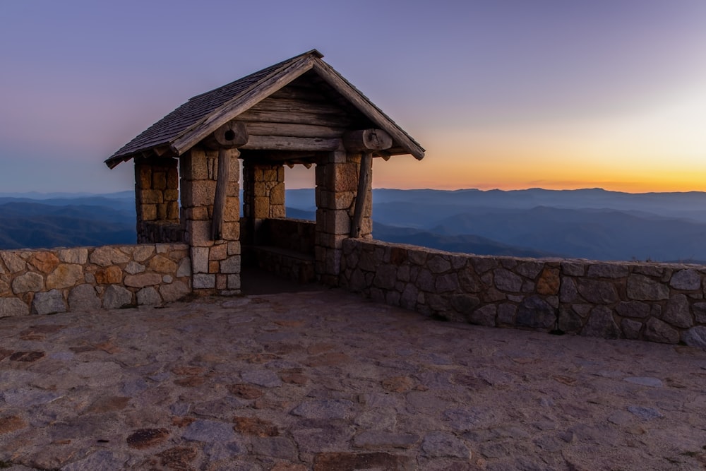 Braunes Holzhaus auf grauem Sand in der Nähe von Gewässern bei Sonnenuntergang