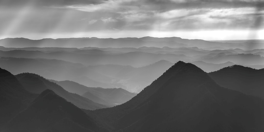 grayscale photo of mountains under cloudy sky