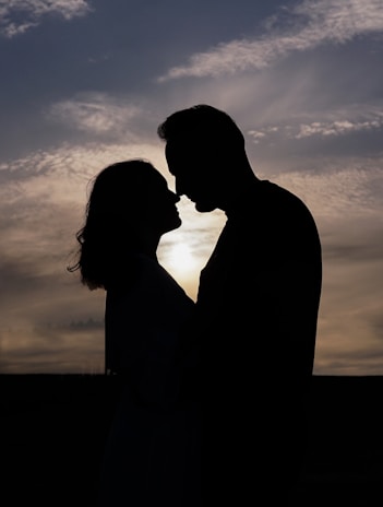 A silhouette of a couple sharing an intimate moment against a sunset backdrop.