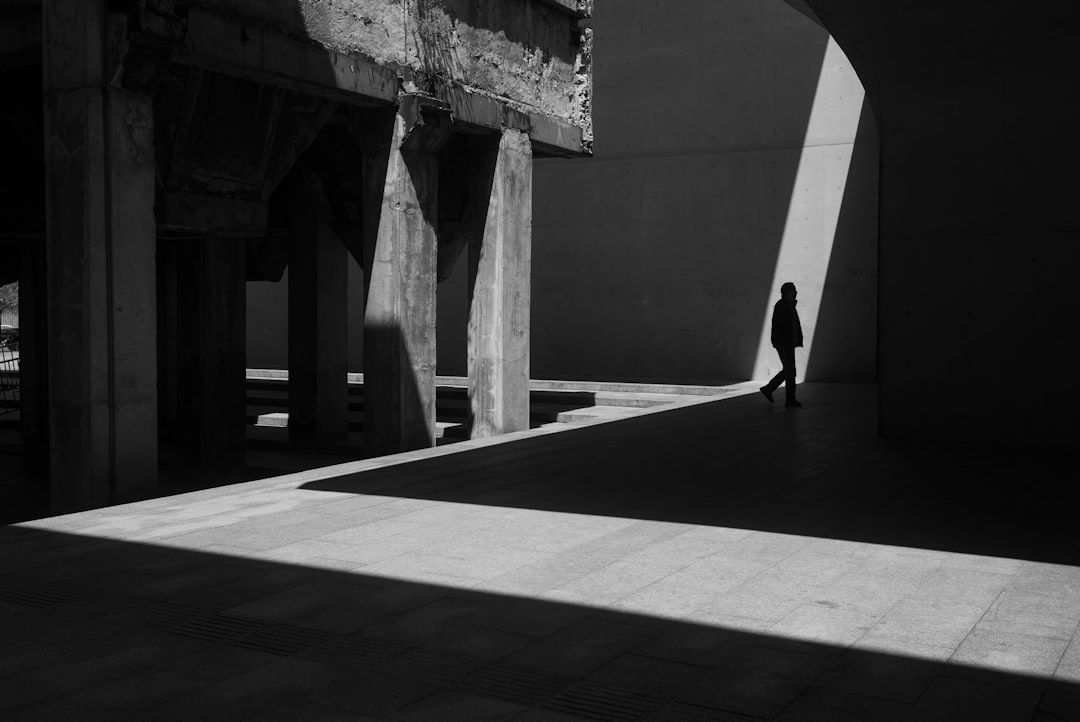 grayscale photo of woman walking on hallway