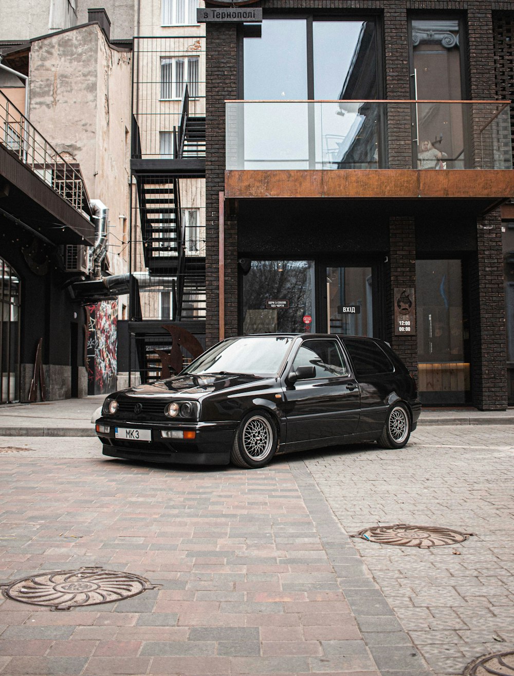 black bmw m 3 parked beside brown building during daytime