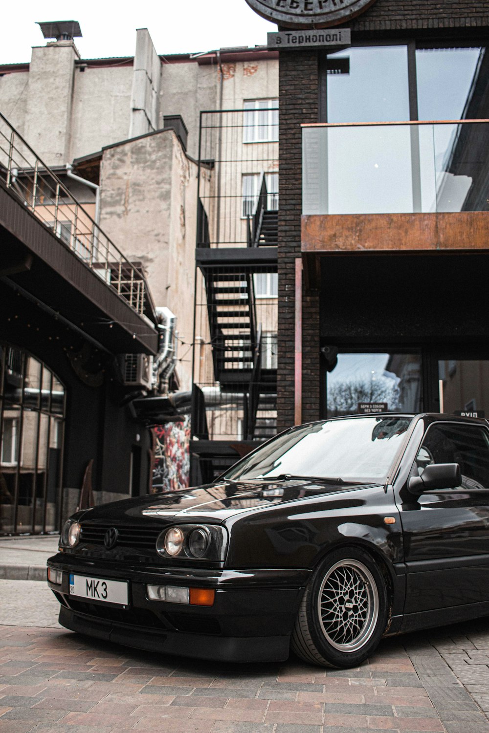 black mercedes benz coupe parked beside brown building during daytime