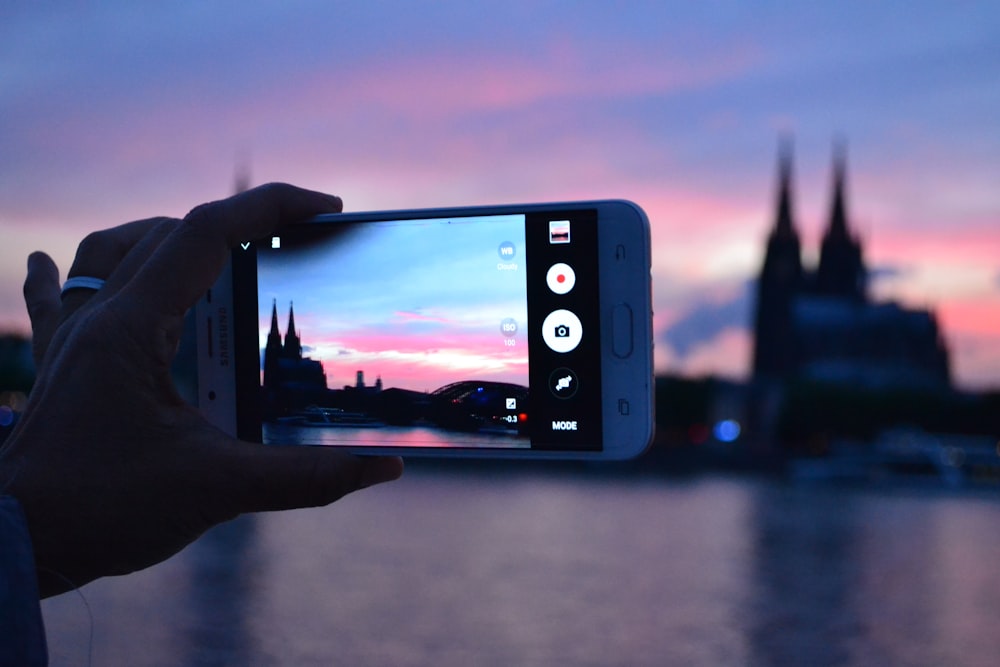 person holding iphone taking photo of building during daytime