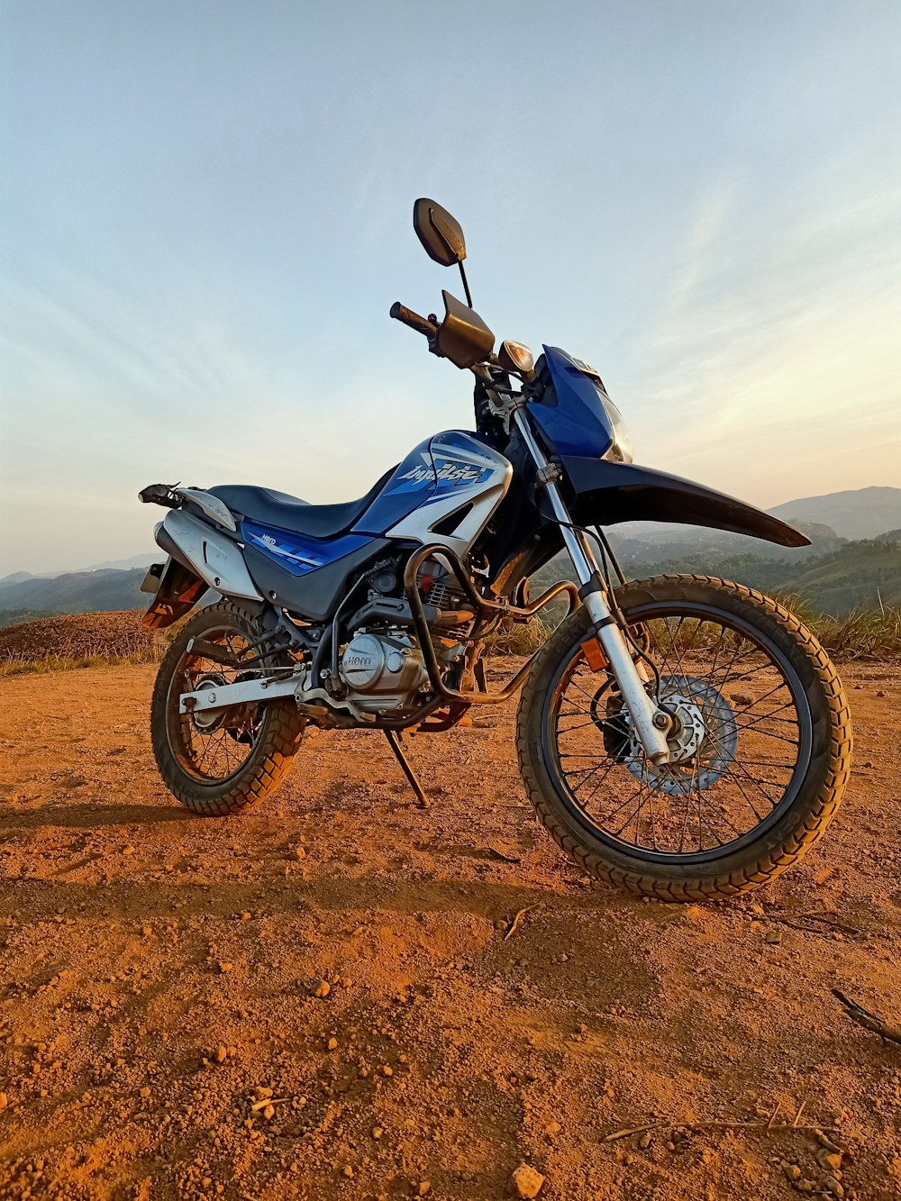 blue and black naked motorcycle on brown sand under white cloudy sky during daytime